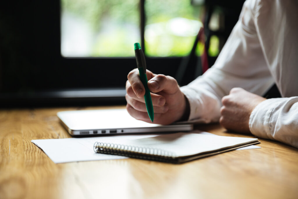 Image of a person at a desk. They're holding a pen above paper as if to check off items on a political campaign checklist.